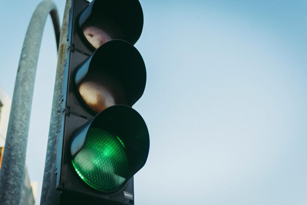 Close-up of a green traffic light against a clear blue sky, symbolizing go and safety.